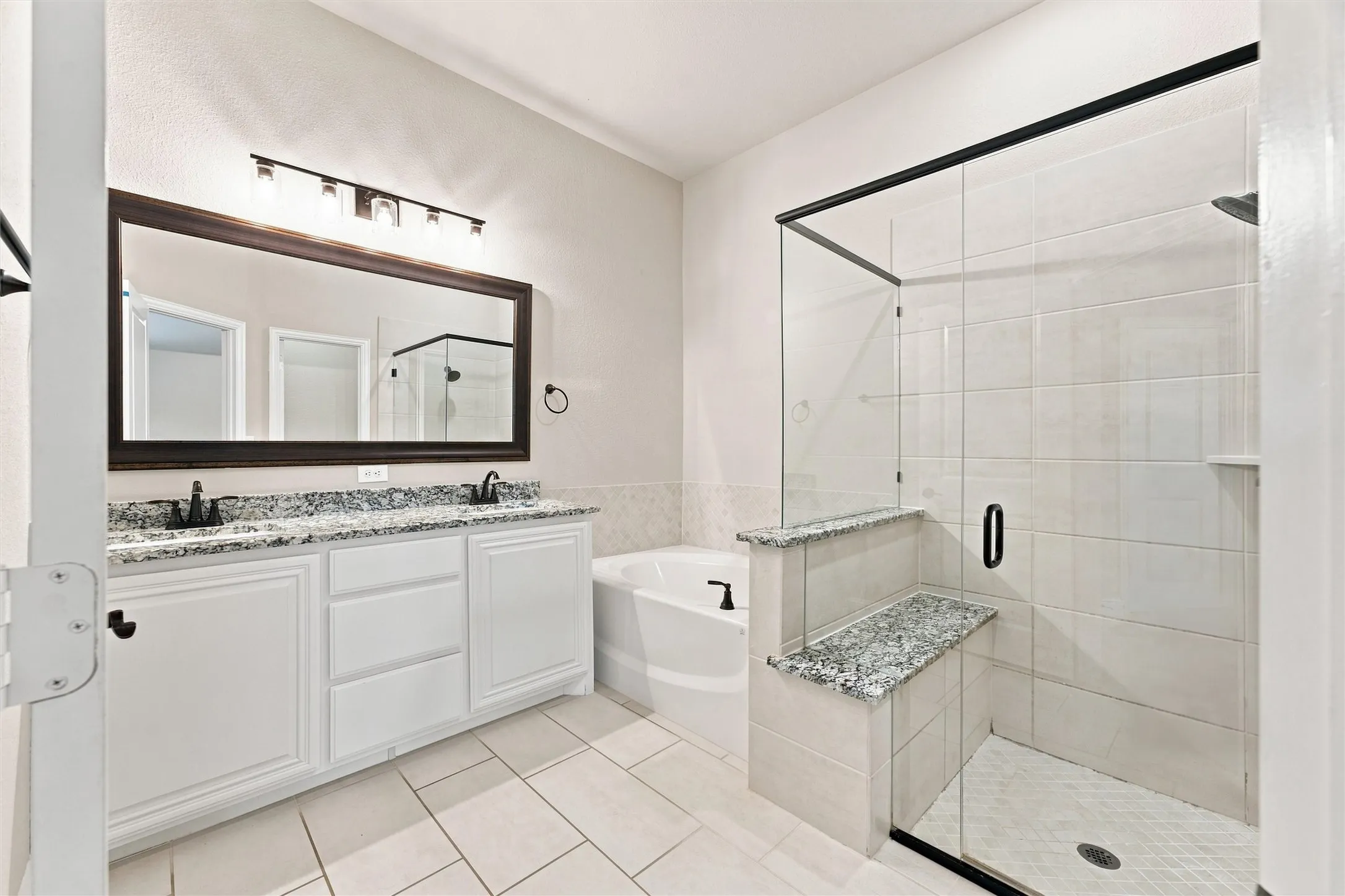 Dual vanity with granite countertops, framed mirror, and matte black fixtures