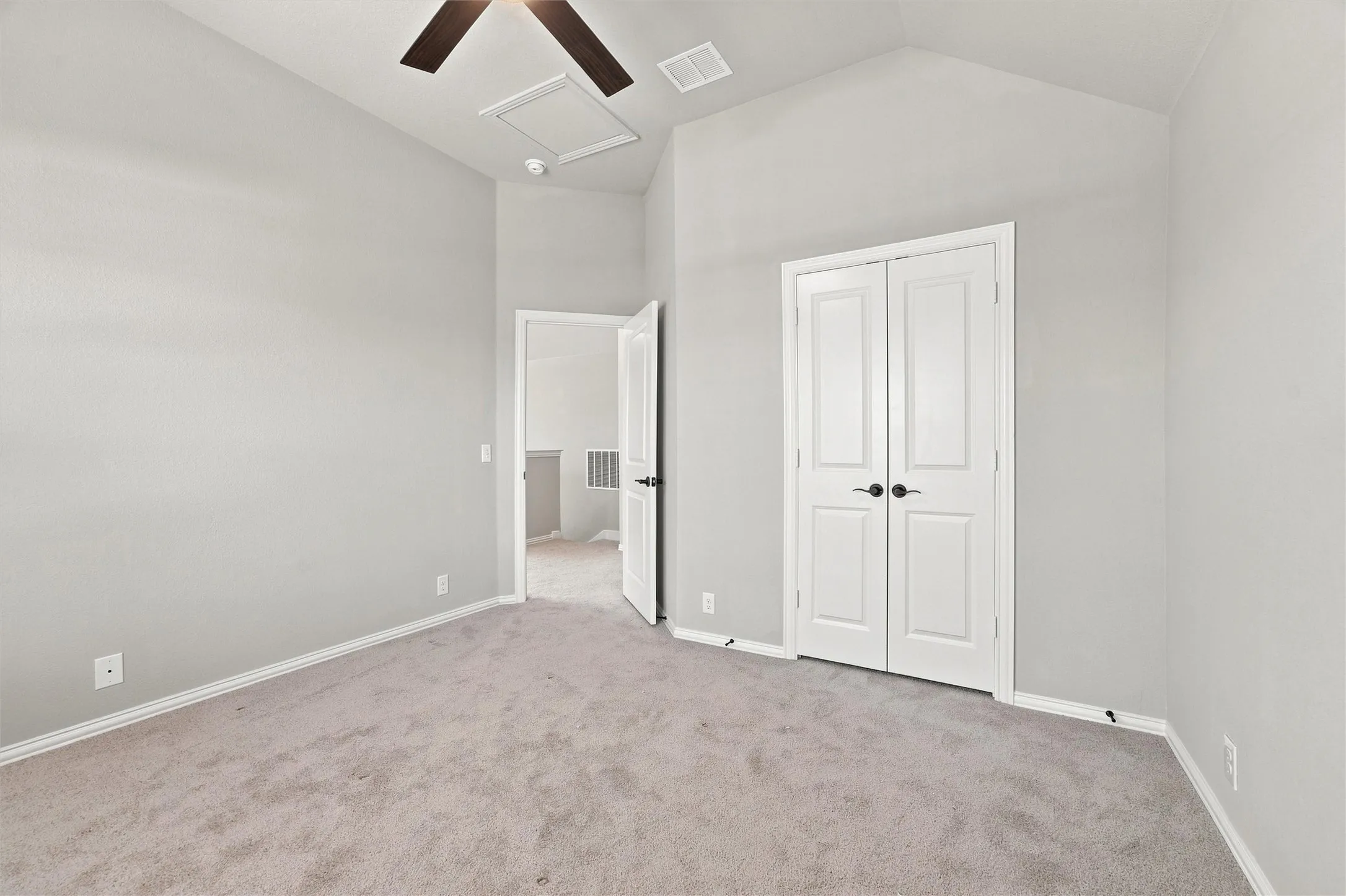 Vaulted ceiling with a ceiling fan, light gray wall finish, light gray carpet flooring, and white bifold doors