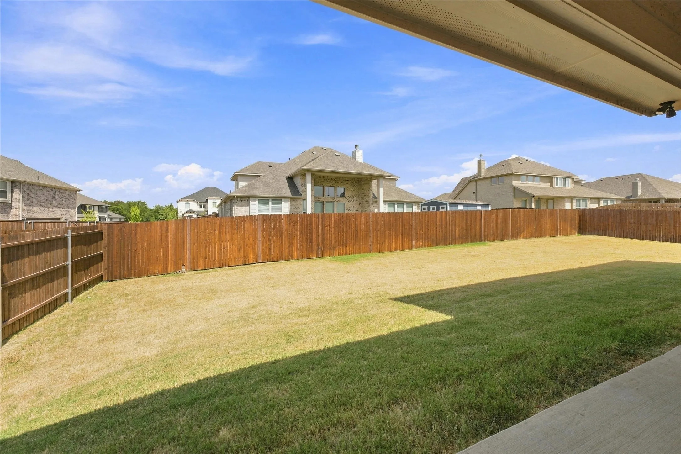 Expansive backyard with a wood privacy fence and a concrete patio