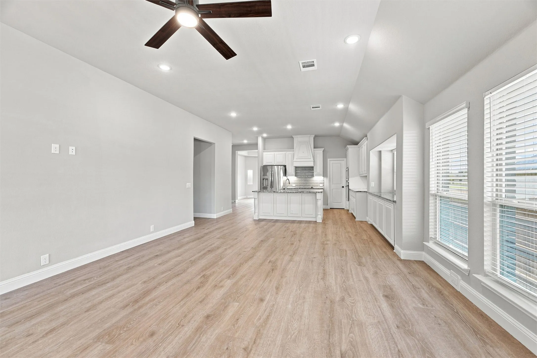 Open-concept living area with wood-finish flooring throughout, recessed lighting, and ceiling fan