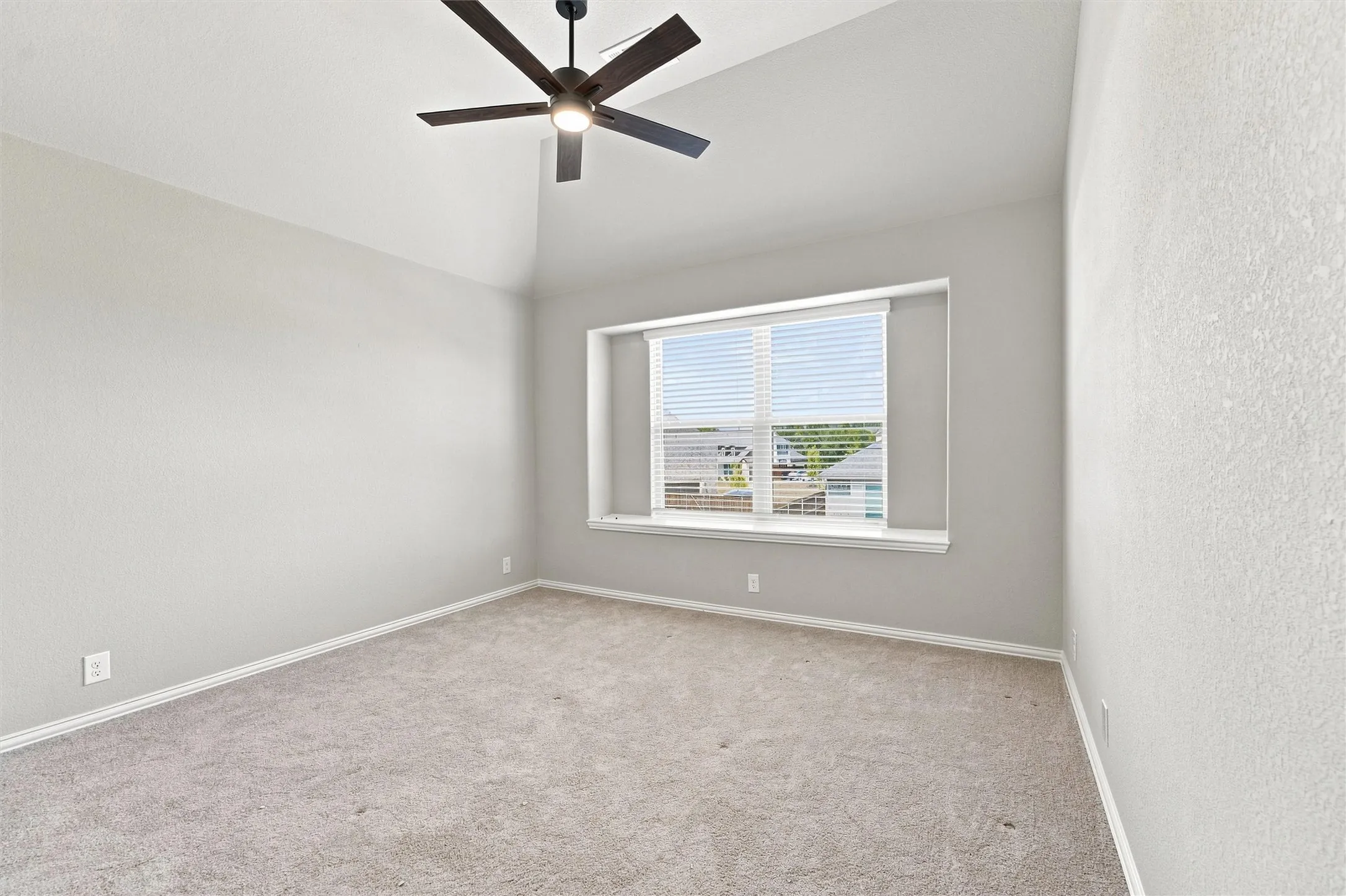Vaulted ceiling with a ceiling fan, neutral carpeting, and a window with blinds