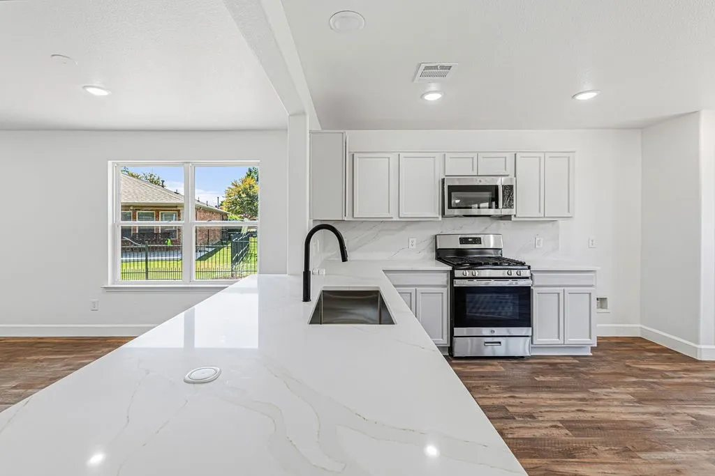 Updated kitchen features quartz countertops and backslash, new appliances, and refreshed white cabinetry