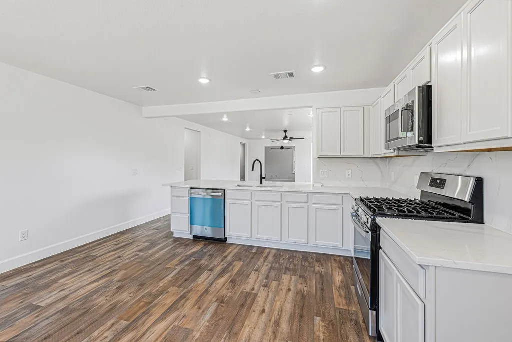 Updated kitchen features quartz countertops and backslash, new appliances, and refreshed white cabinetry