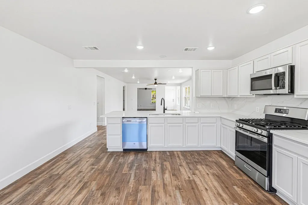 Updated kitchen features quartz countertops and backslash, new appliances, and refreshed white cabinetry