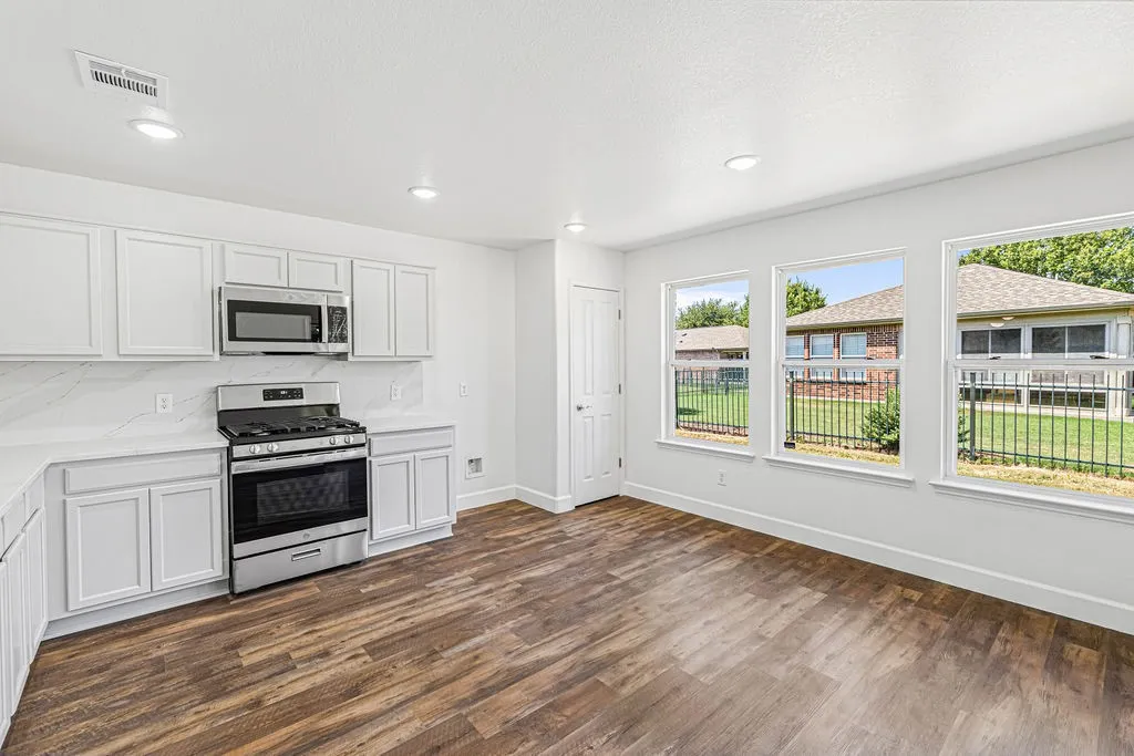 Updated kitchen features quartz countertops and backslash, new appliances, and refreshed white cabinetry