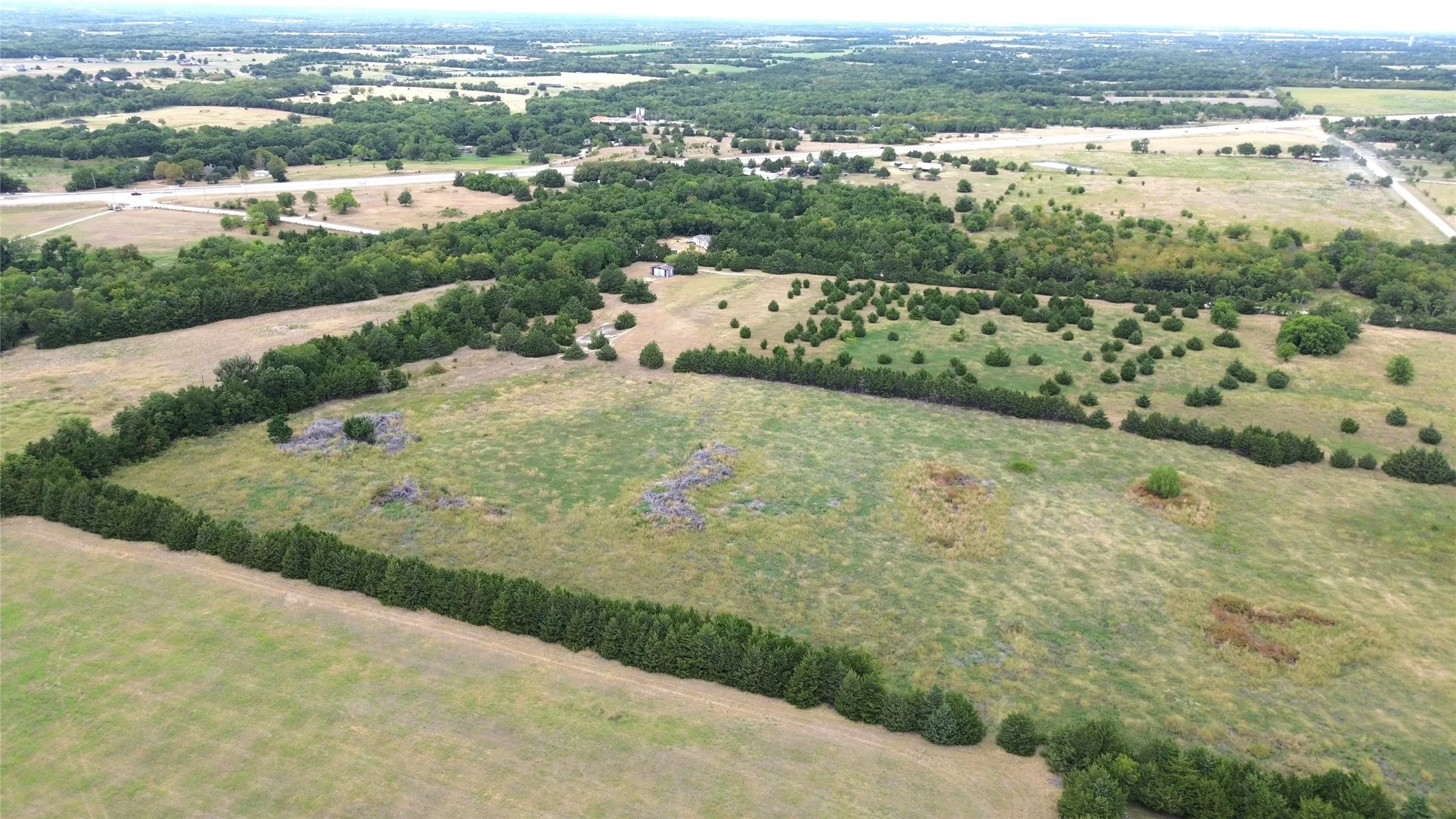 Expansive undeveloped land featuring a combination of open fields and varied tree coverage