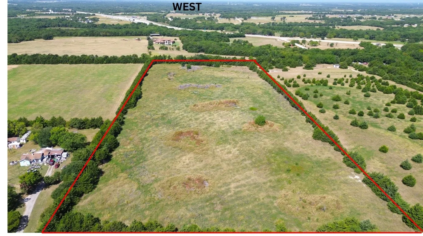 Expansive open land with varying vegetation, defined by prominent tree lines along the perimeter