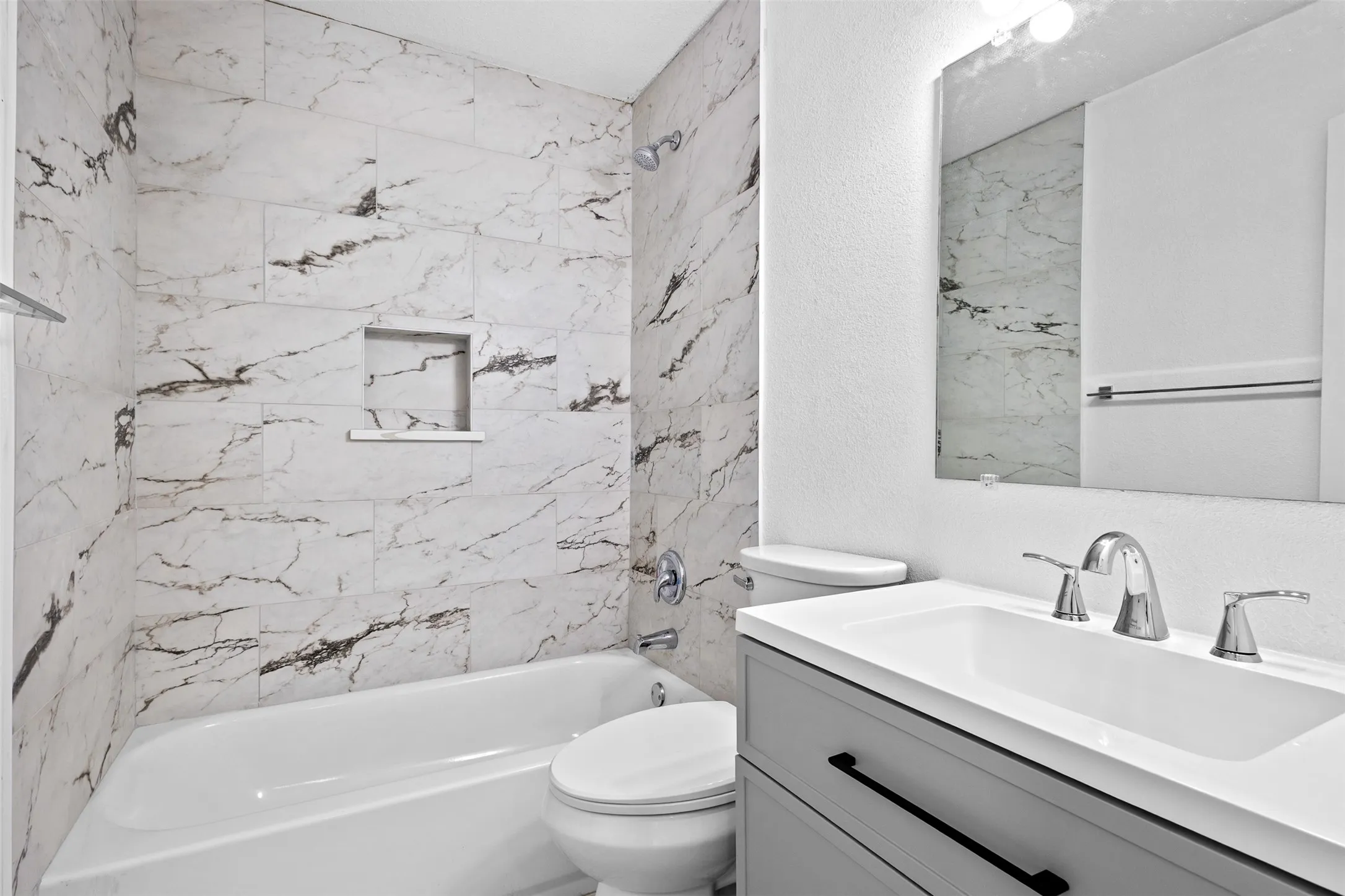 Tiled shower surround with integrated niche, chrome fixtures, and a white soaking tub