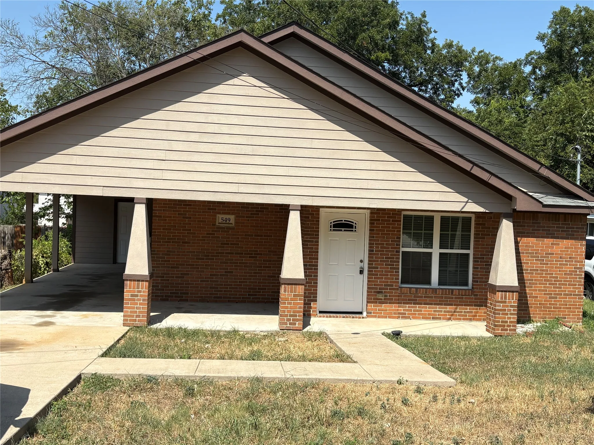 Brick and siding exterior with a front entry, carport, and concrete walkway