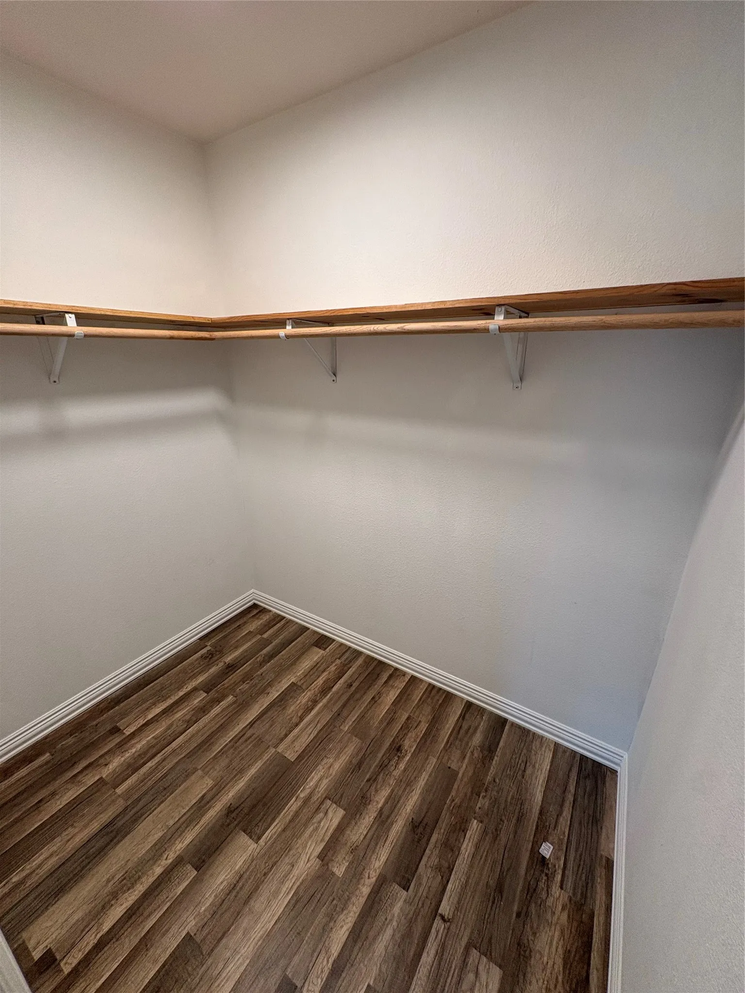 Wood-finish flooring with white trim, featuring built-in shelving and hanging rods