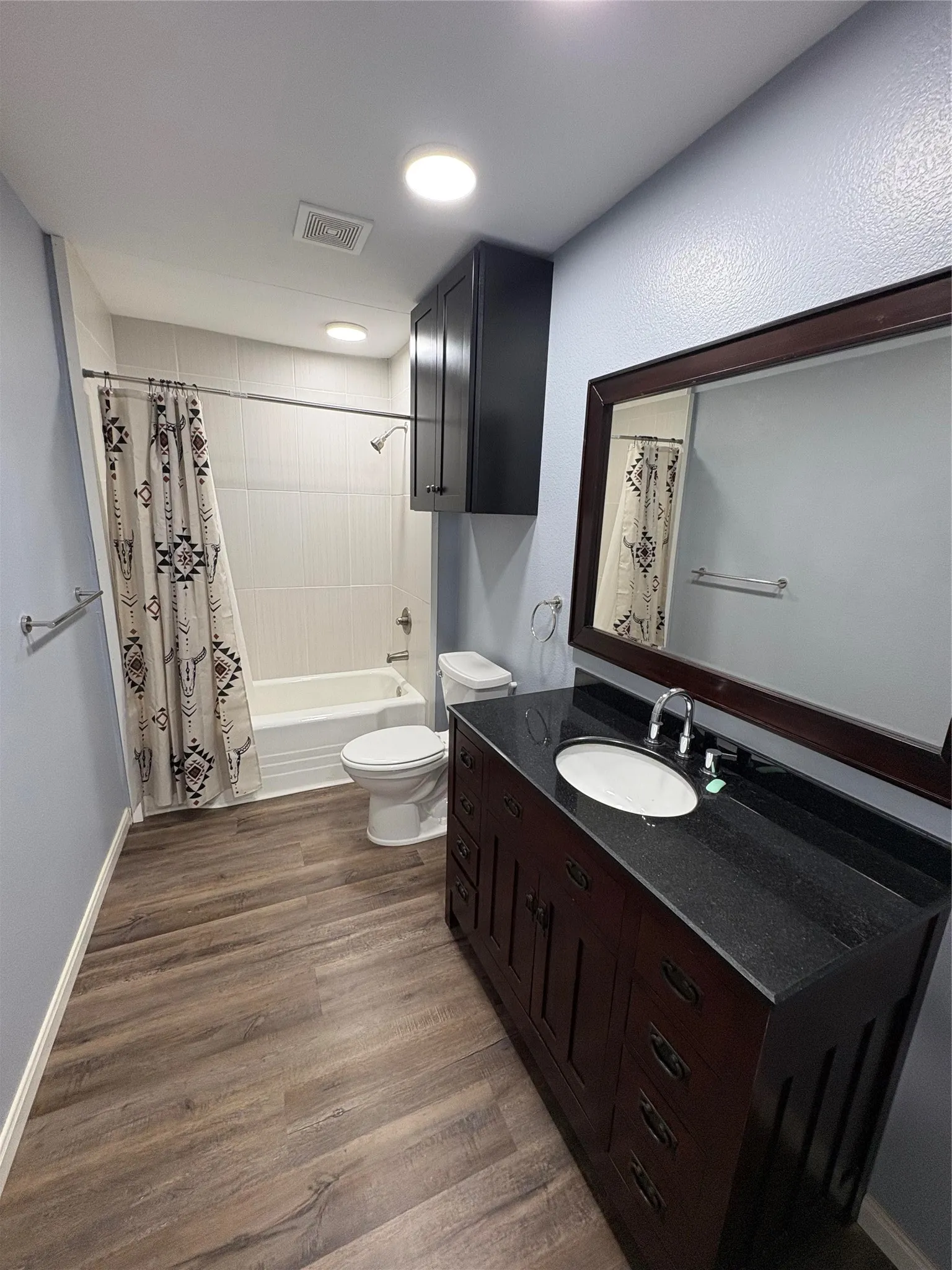 Vanity with an integrated sink, dark countertop, and wood-finish cabinetry