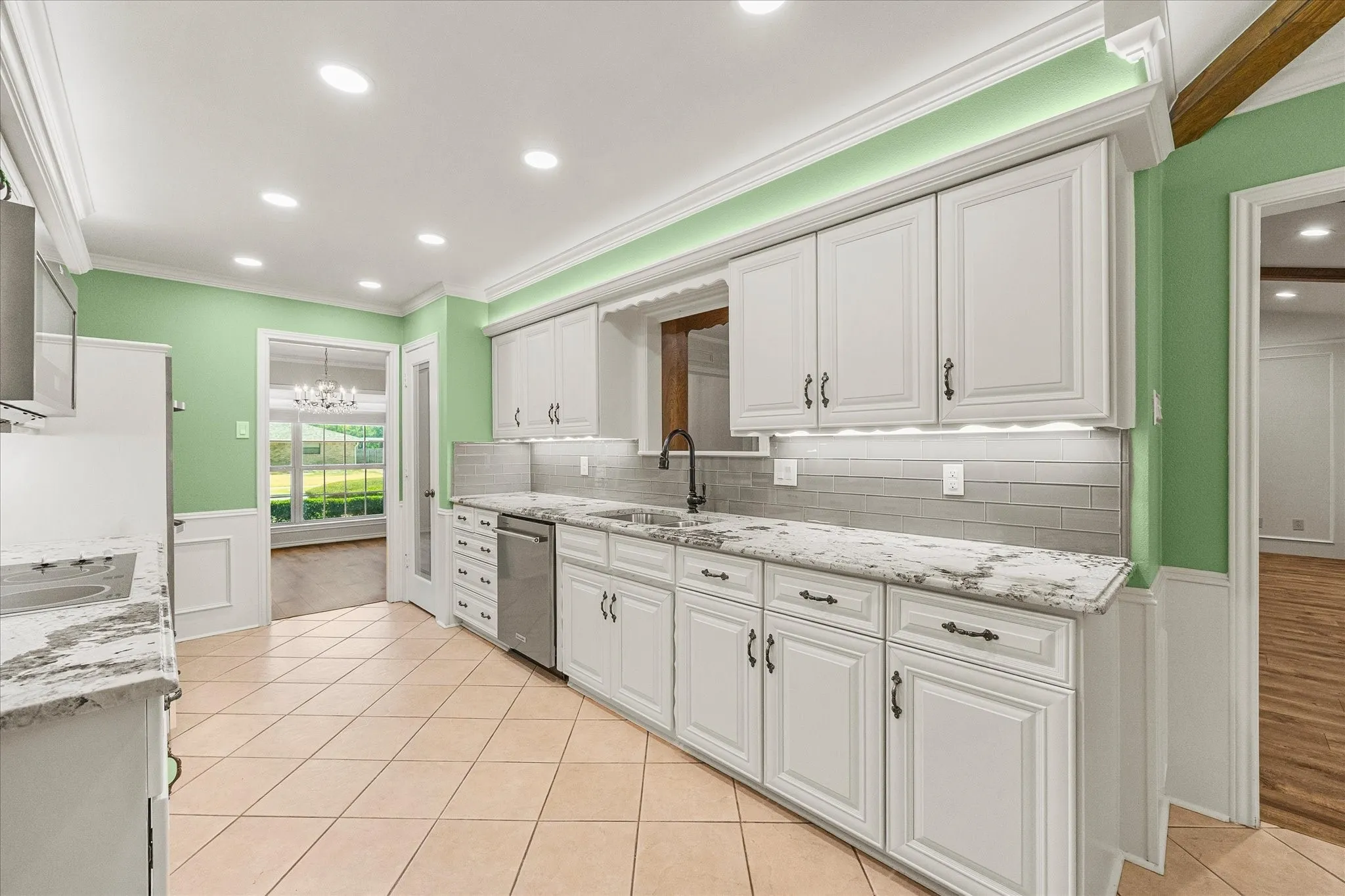 Updated kitchen with granite countertops, undercounter lighting, above-cabinet lighting, updated and abundant cabinetry, and stylish tile backsplash.