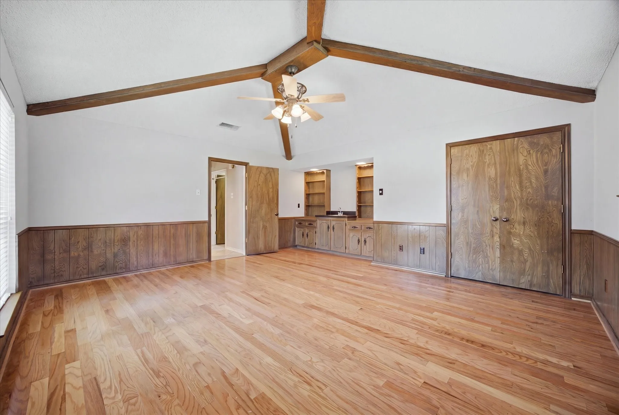 This spacious room with vaulted beamed ceiling could be a bedroom, game room, home gym...make it your own.  Built-in cabinets, shelves and also a sink!