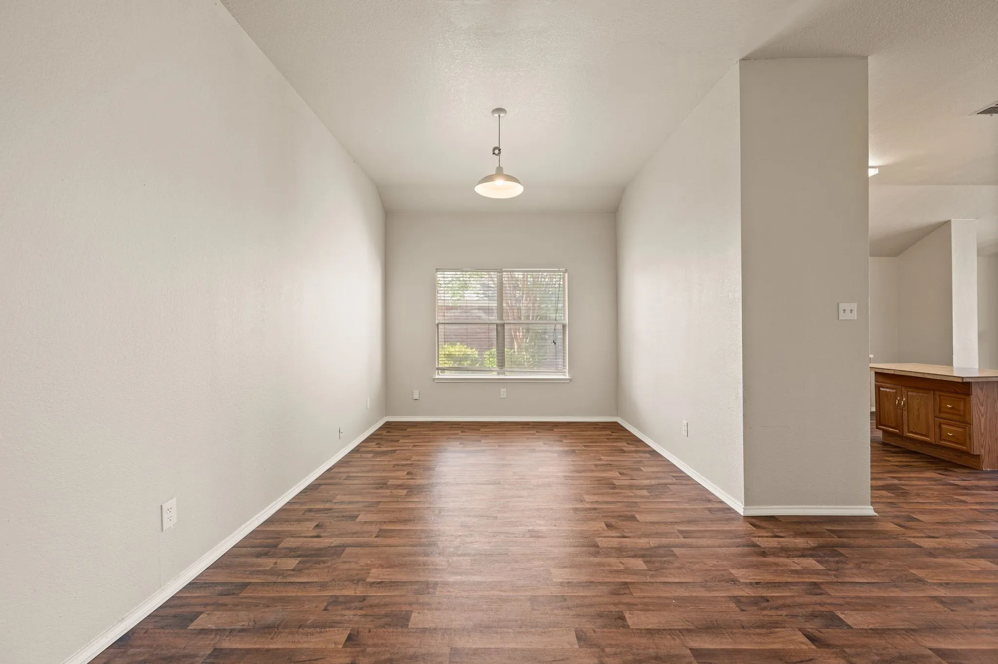Wood-finish flooring, single-pane window, flush-mount pendant light, light neutral wall paint