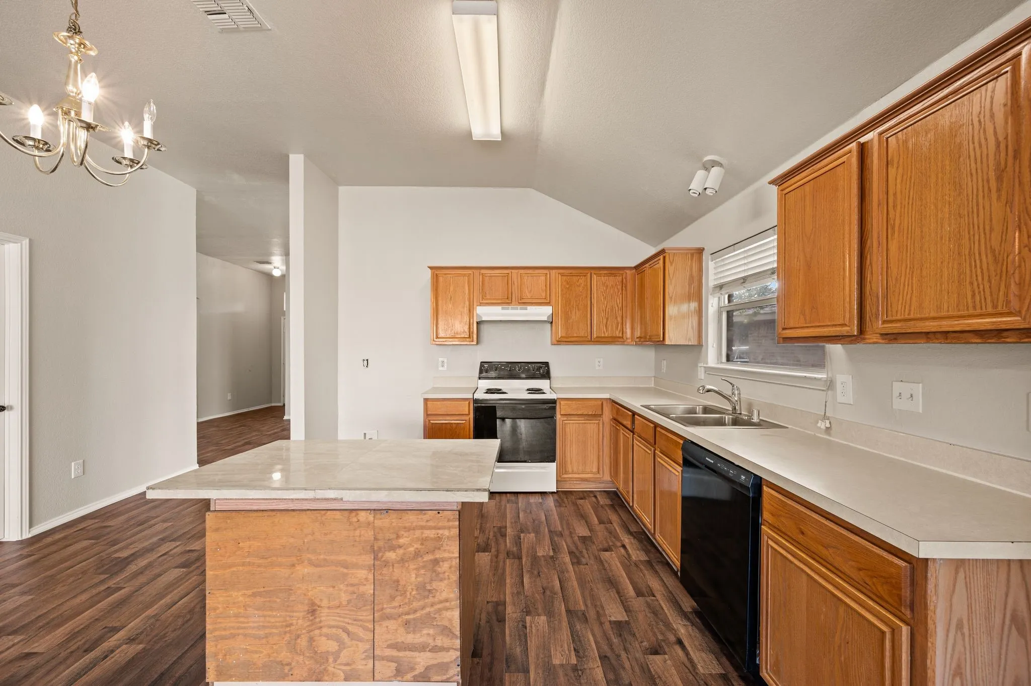 Kitchen featuring wood-finish flooring, wood cabinetry, light-toned countertops, and a full suite of appliances