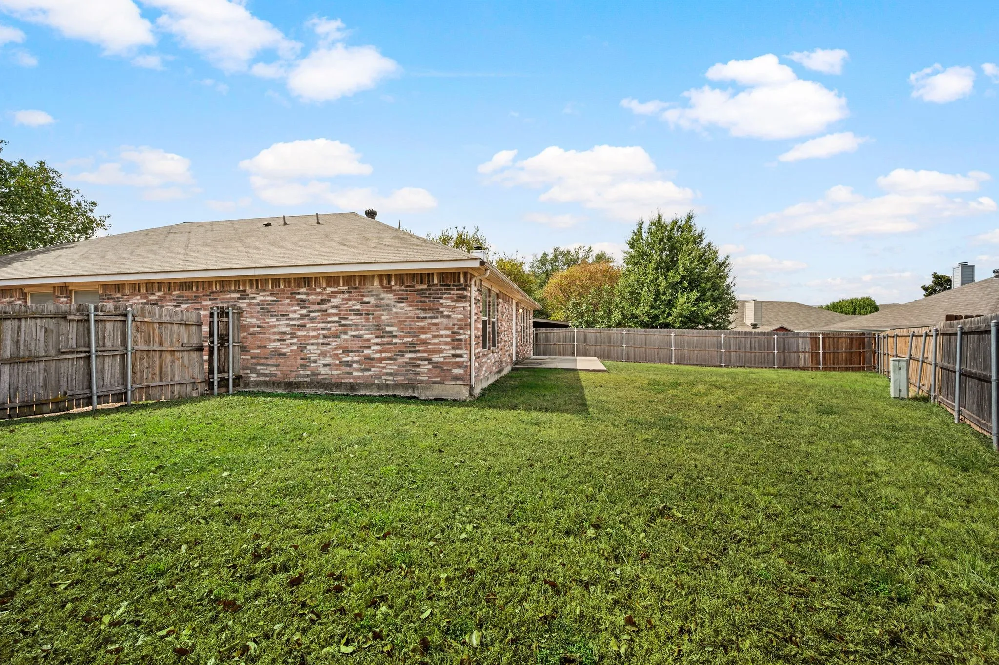 Expansive grassy yard with wood fencing and a concrete patio