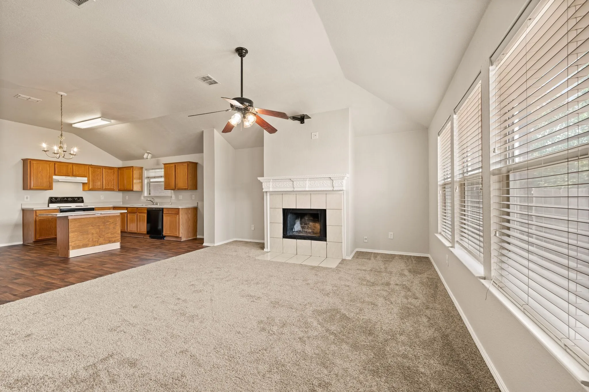 Vaulted ceilings, wood-finish flooring, a tile fireplace, and multiple windows