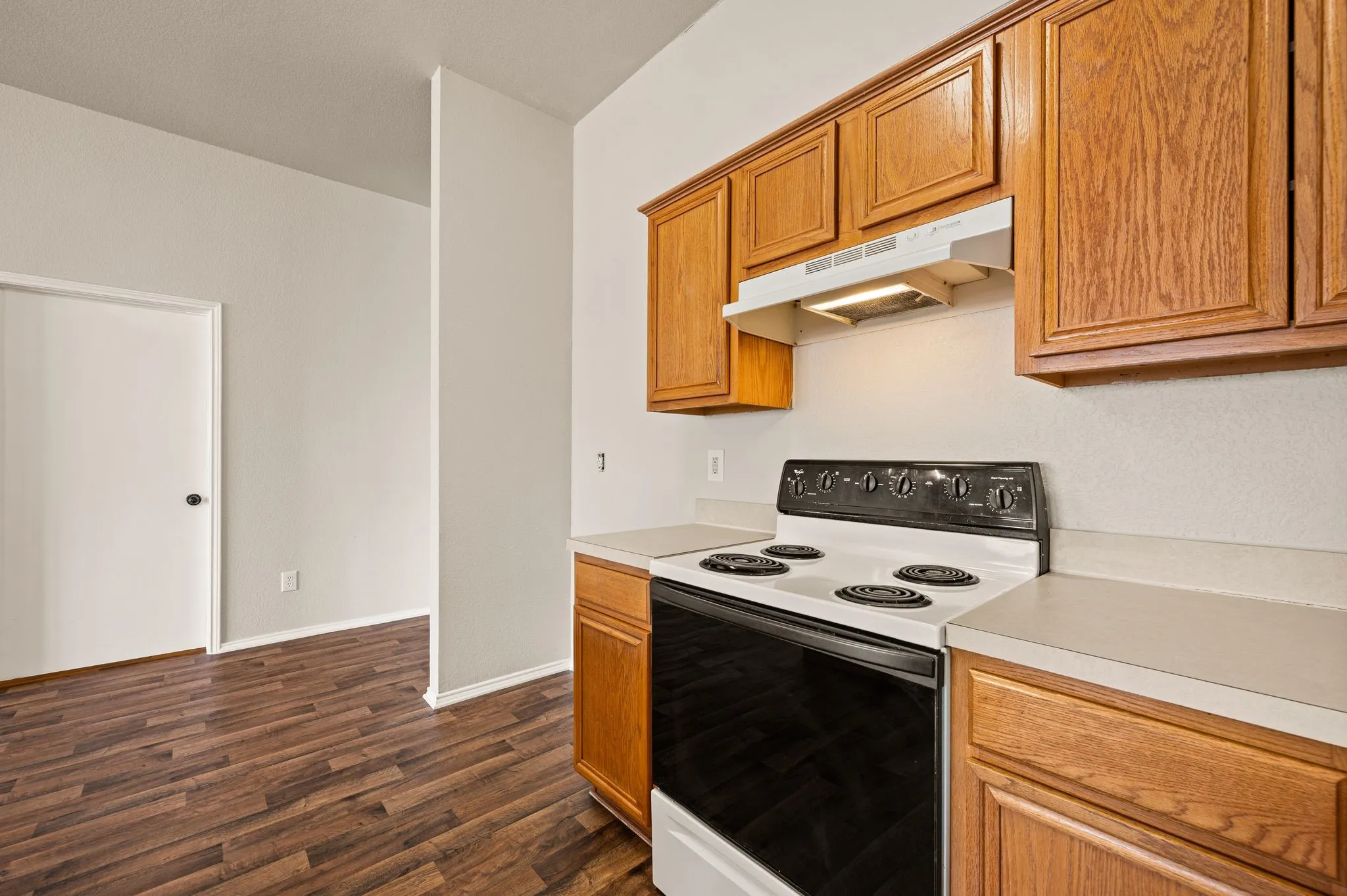 Kitchen area featuring wood-finish flooring, wood cabinetry, and a built-in range with a hood