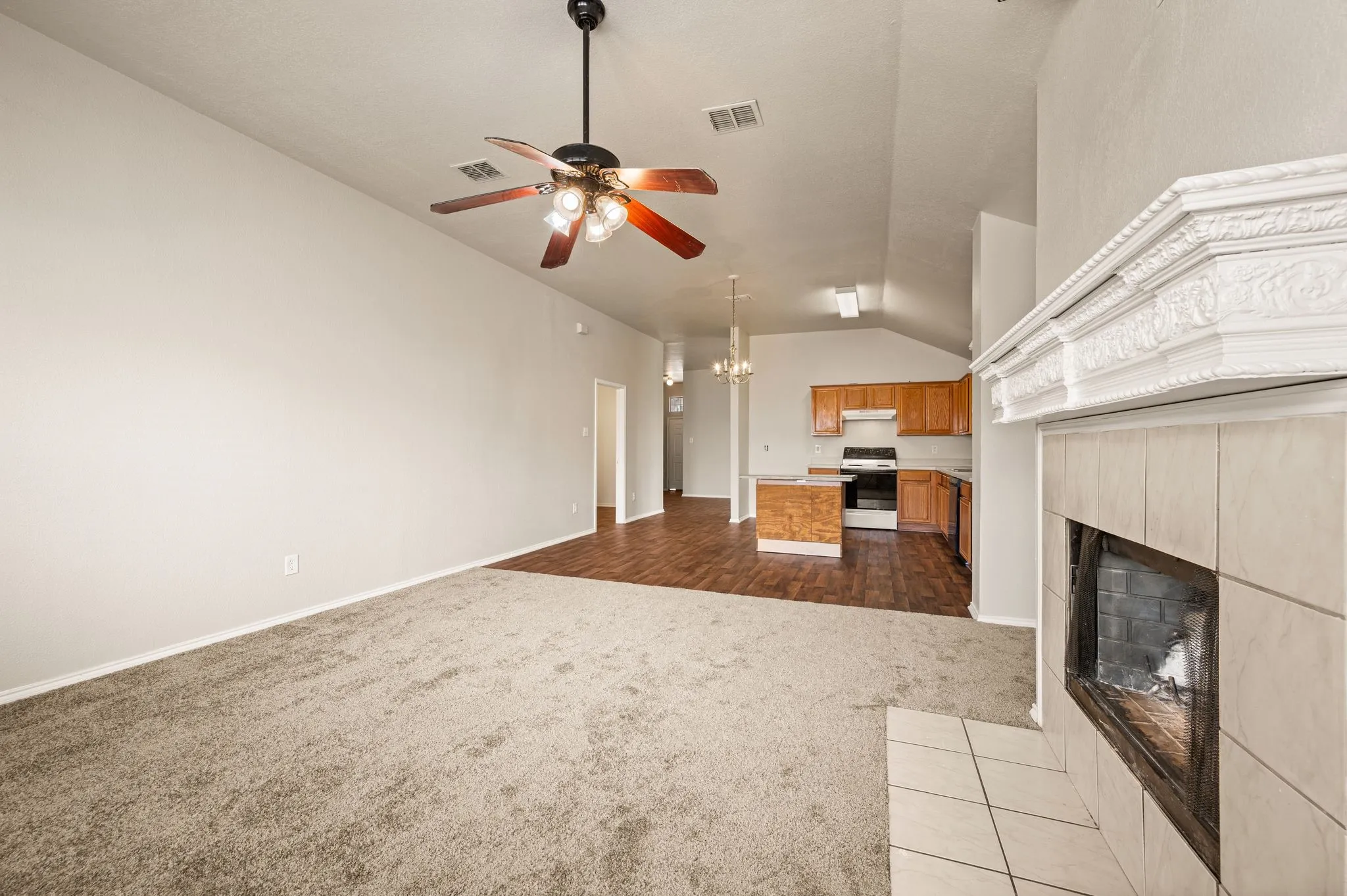 Carpeted living space with a vaulted ceiling and a ceiling fan