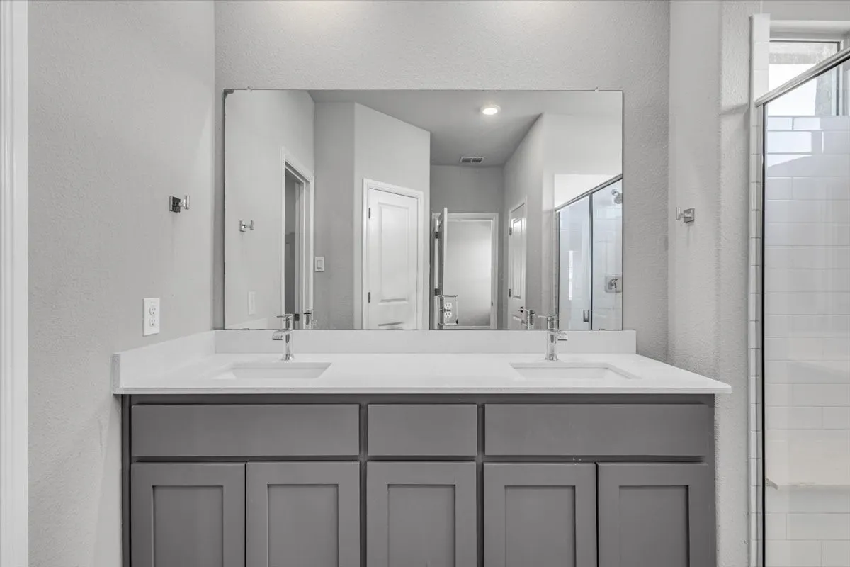 Dual vanity with gray cabinetry, white countertops, and chrome fixtures