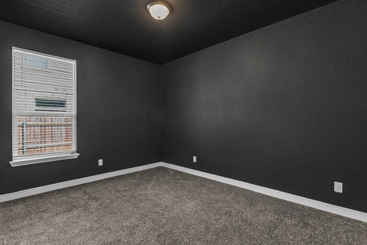 Room featuring dark textured walls, coordinating ceiling, light-colored trim, and a window with blinds