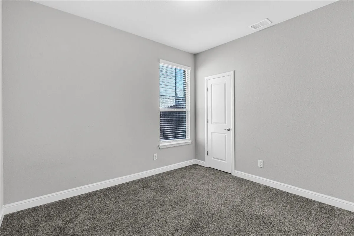 Light gray painted walls, window with blinds, white trim, and gray carpeting