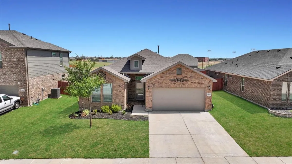 Brick facade residence with an attached two-car garage, concrete driveway, and a well-maintained lawn