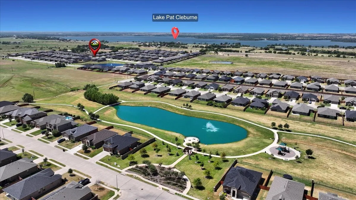 Community with a central pond feature, landscaped green spaces, paved walking paths, and residential properties