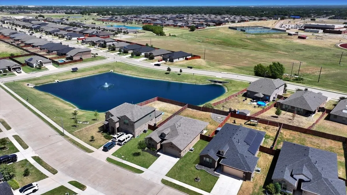 Residential community featuring single-family homes, a central water feature with a fountain, and paved streets