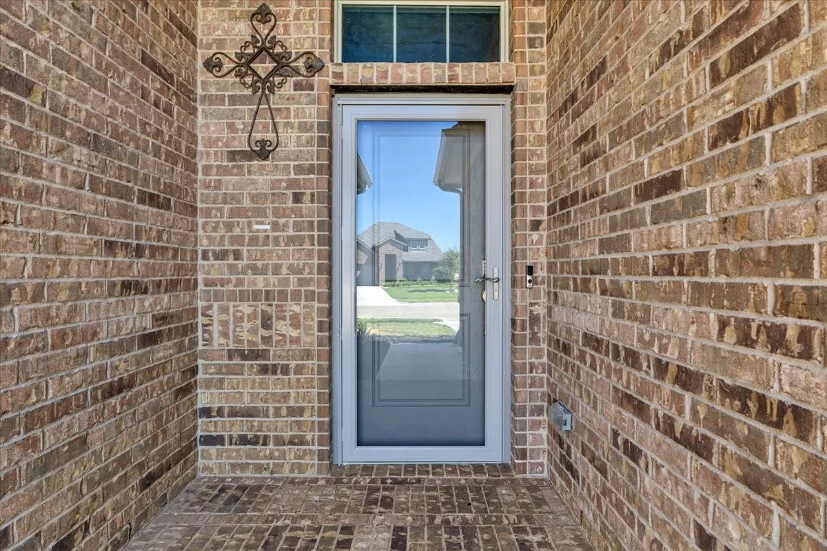 Brick exterior with a storm door, transom window, and brick-patterned porch flooring