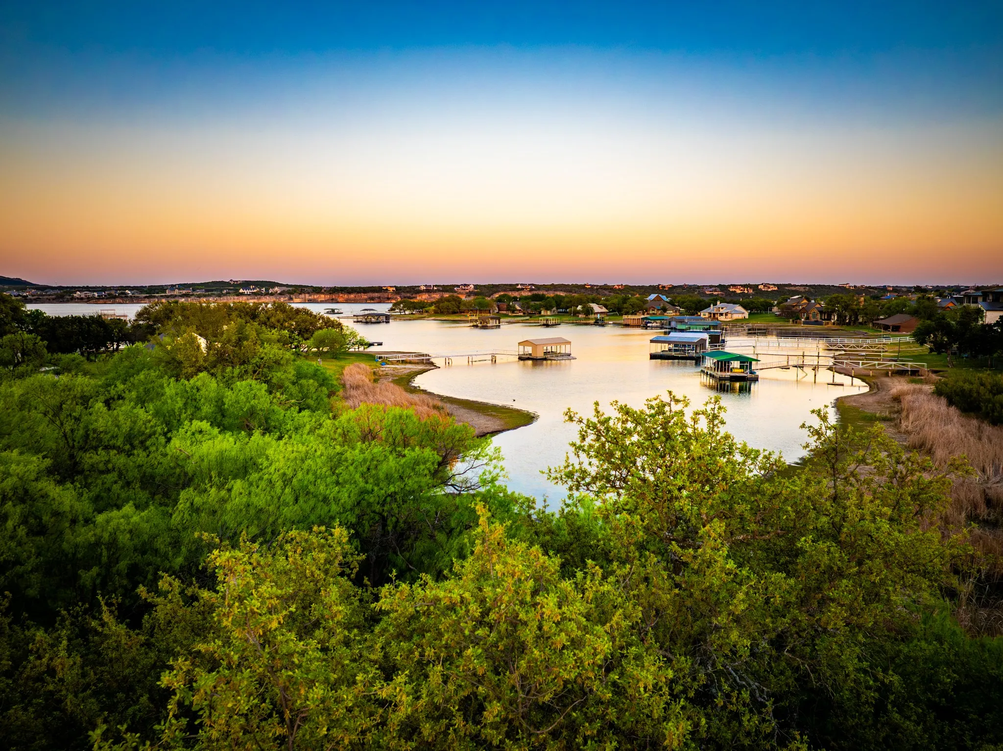 Lakefront setting with multiple boat docks, surrounding residential properties, and abundant mature trees