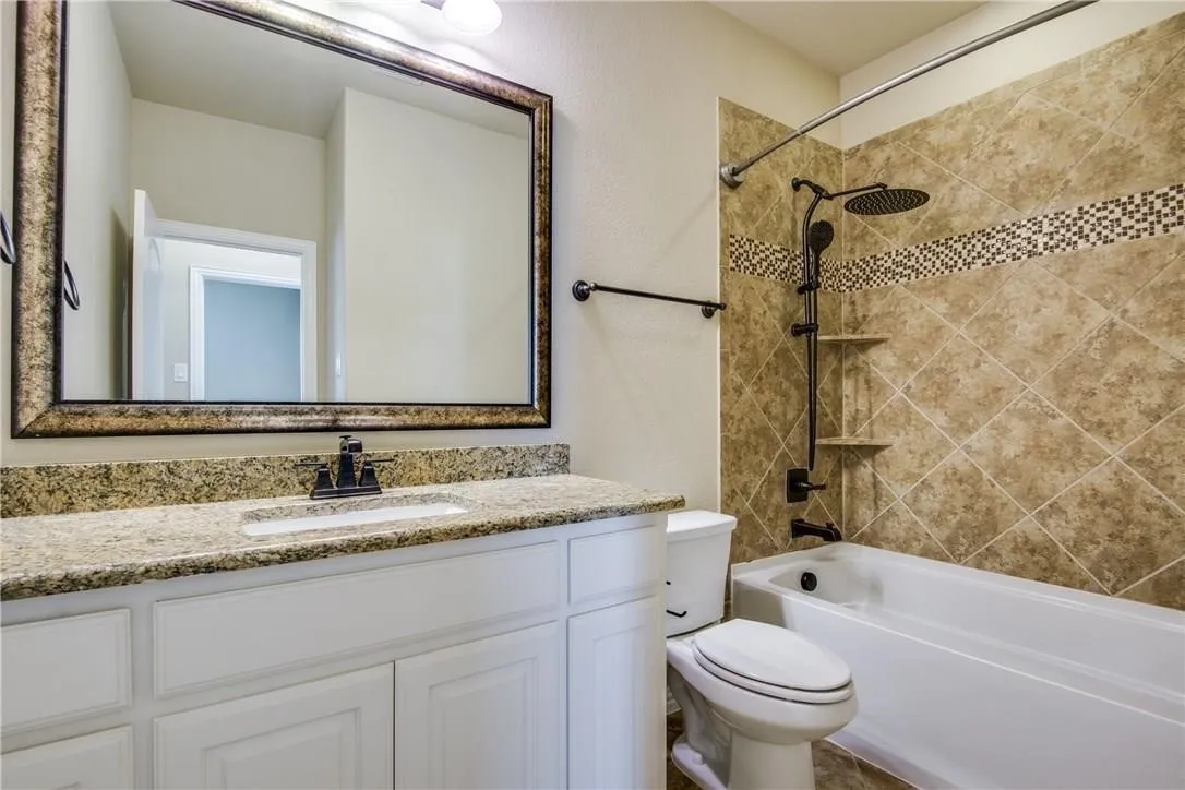 Bathroom featuring a white vanity with a granite countertop, undermount sink, and a framed mirror