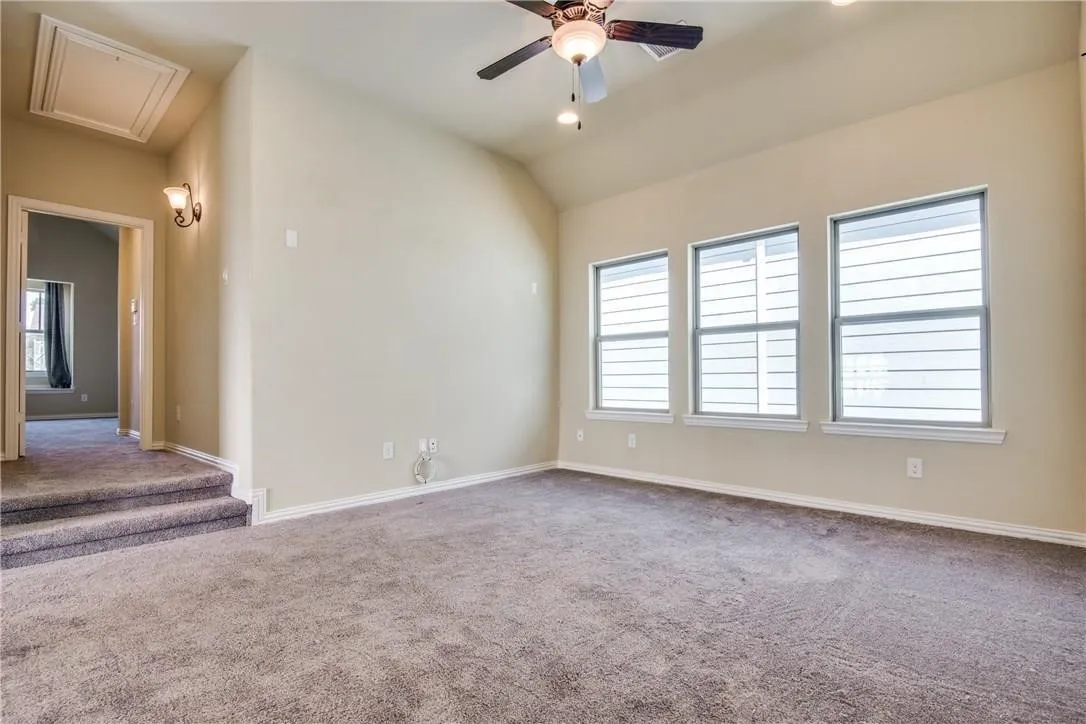 Vaulted ceiling with ceiling fan, recessed lighting, three windows, and carpeted flooring