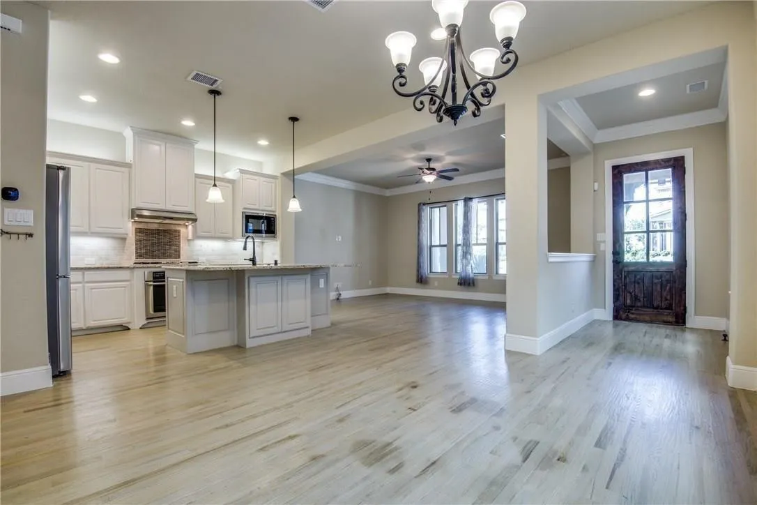 Open-concept living area featuring light wood-finish flooring, recessed lighting, and a kitchen island with pendant lights