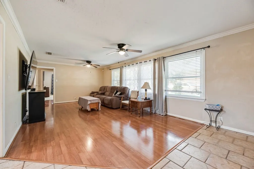 Spacious room featuring wood-finish flooring, crown molding, and multiple windows