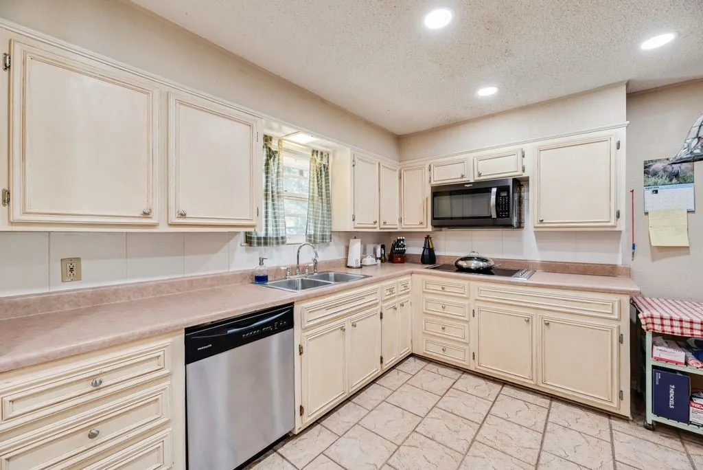Kitchen featuring cream-painted cabinetry, a double basin stainless steel sink, a stainless steel dishwasher, a built-in microwave, and recessed lighting