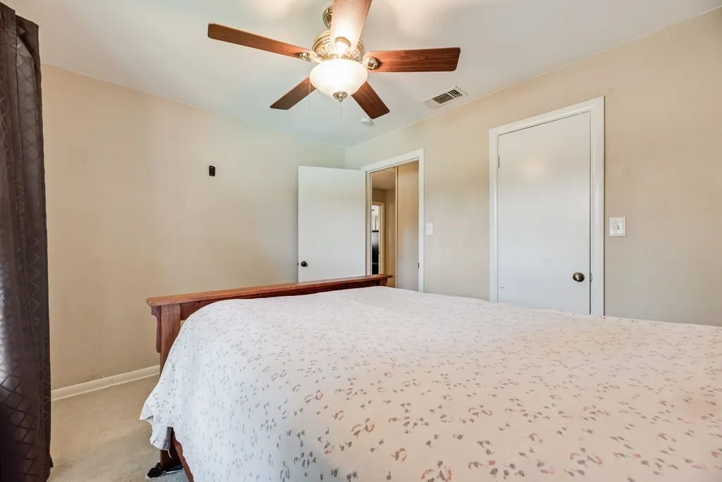 Ceiling fan with light fixture, neutral wall color, white trim, and light-colored carpeting