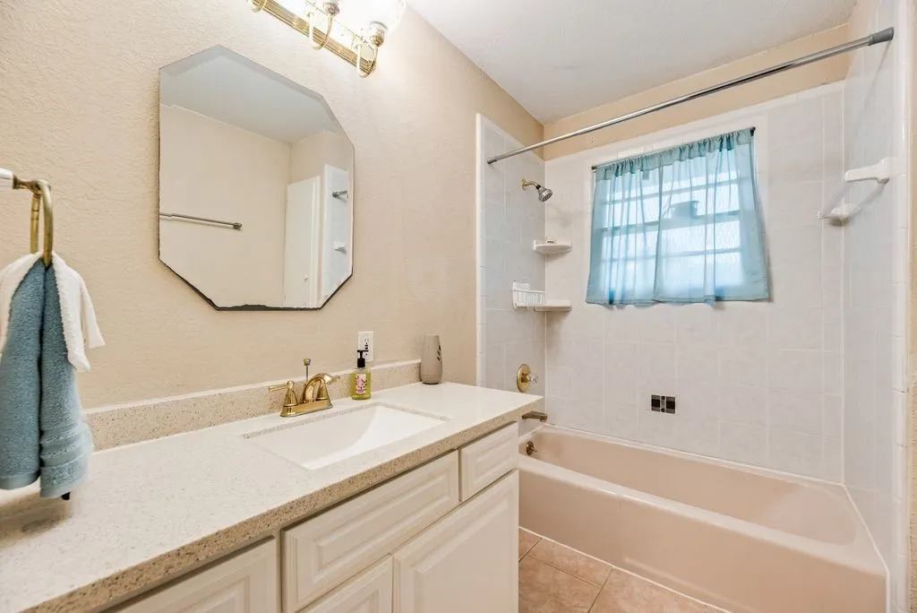 Vanity with an integrated sink, polished brass faucet, and a large octagonal mirror