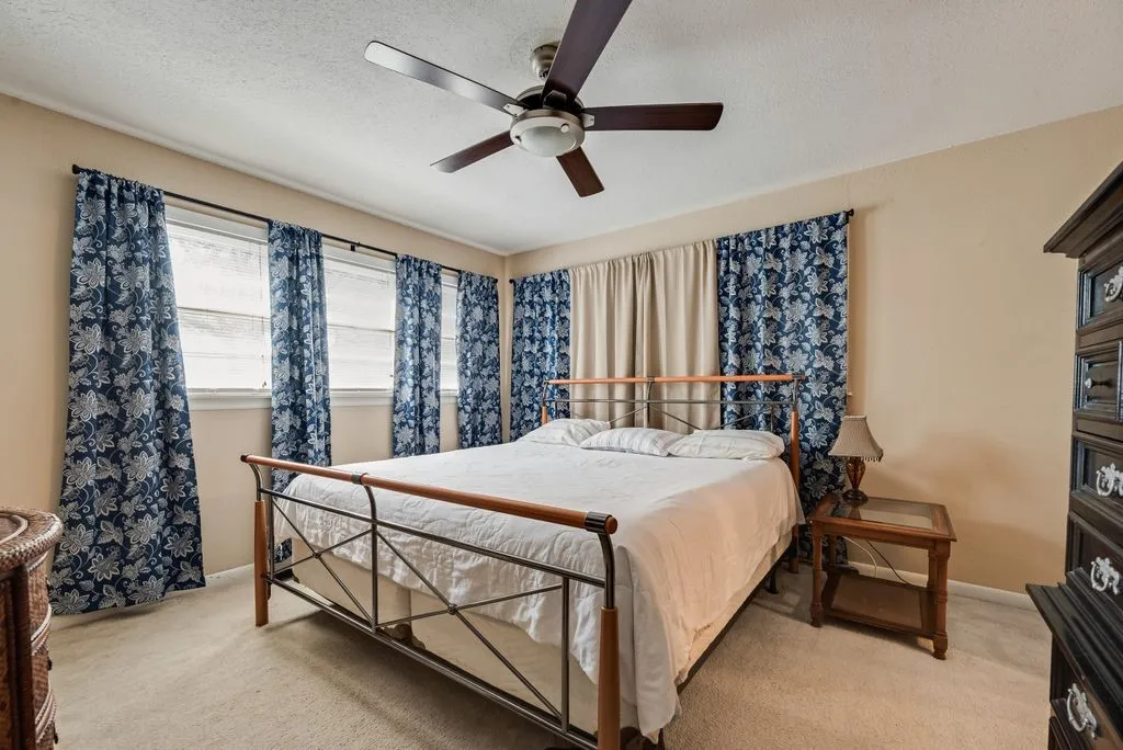 Neutral wall color, carpeted flooring, ceiling fan, multiple windows