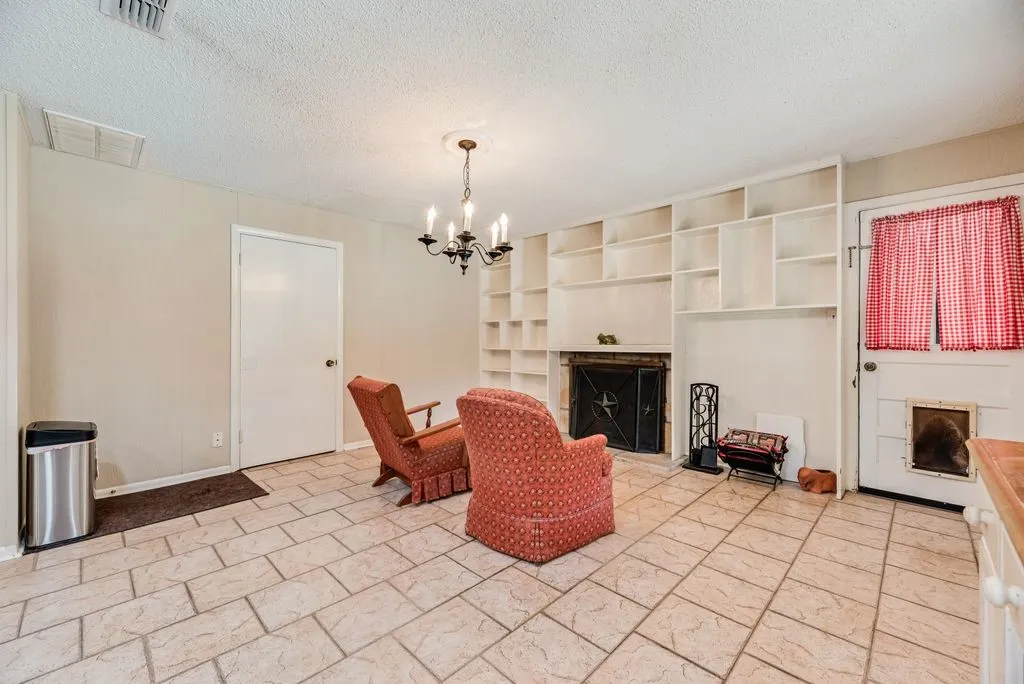 Built-in shelving, tile flooring, built-in fireplace, ceiling-mounted chandelier, paneled walls