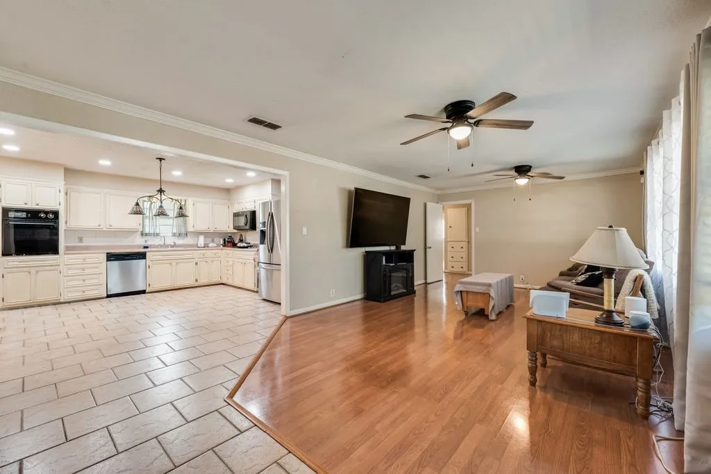 Open-concept living area with wood-finish flooring and two ceiling fans