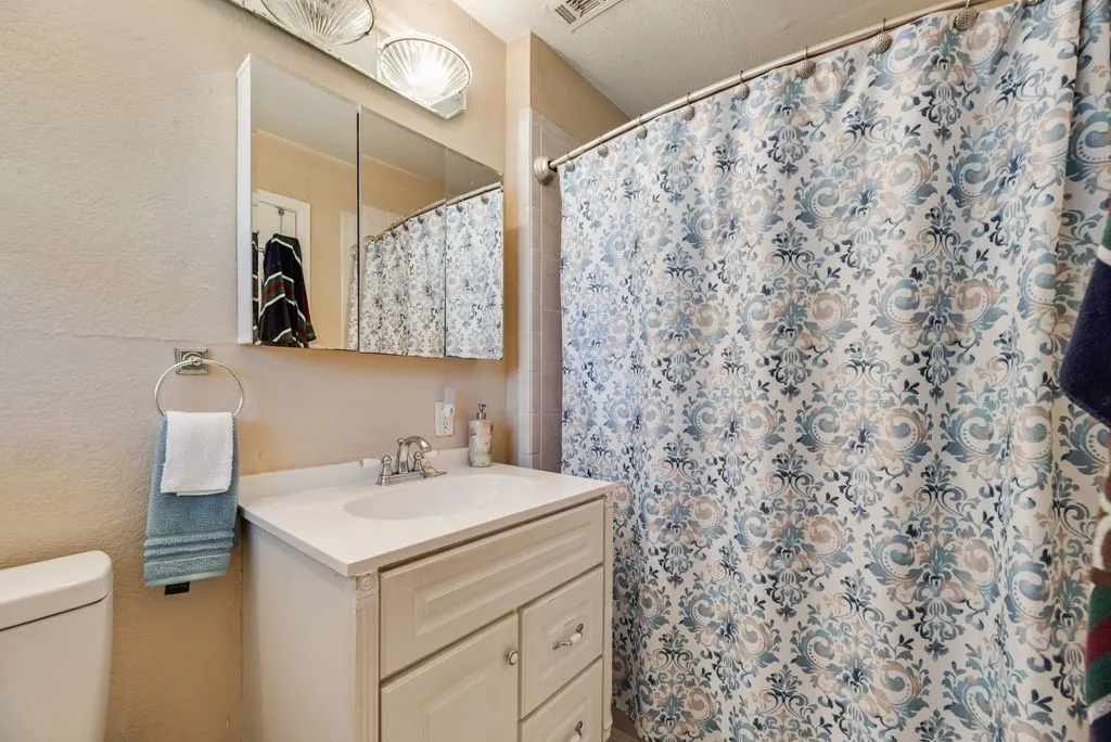 White vanity with cabinet storage, recessed medicine cabinet, and chrome faucet
