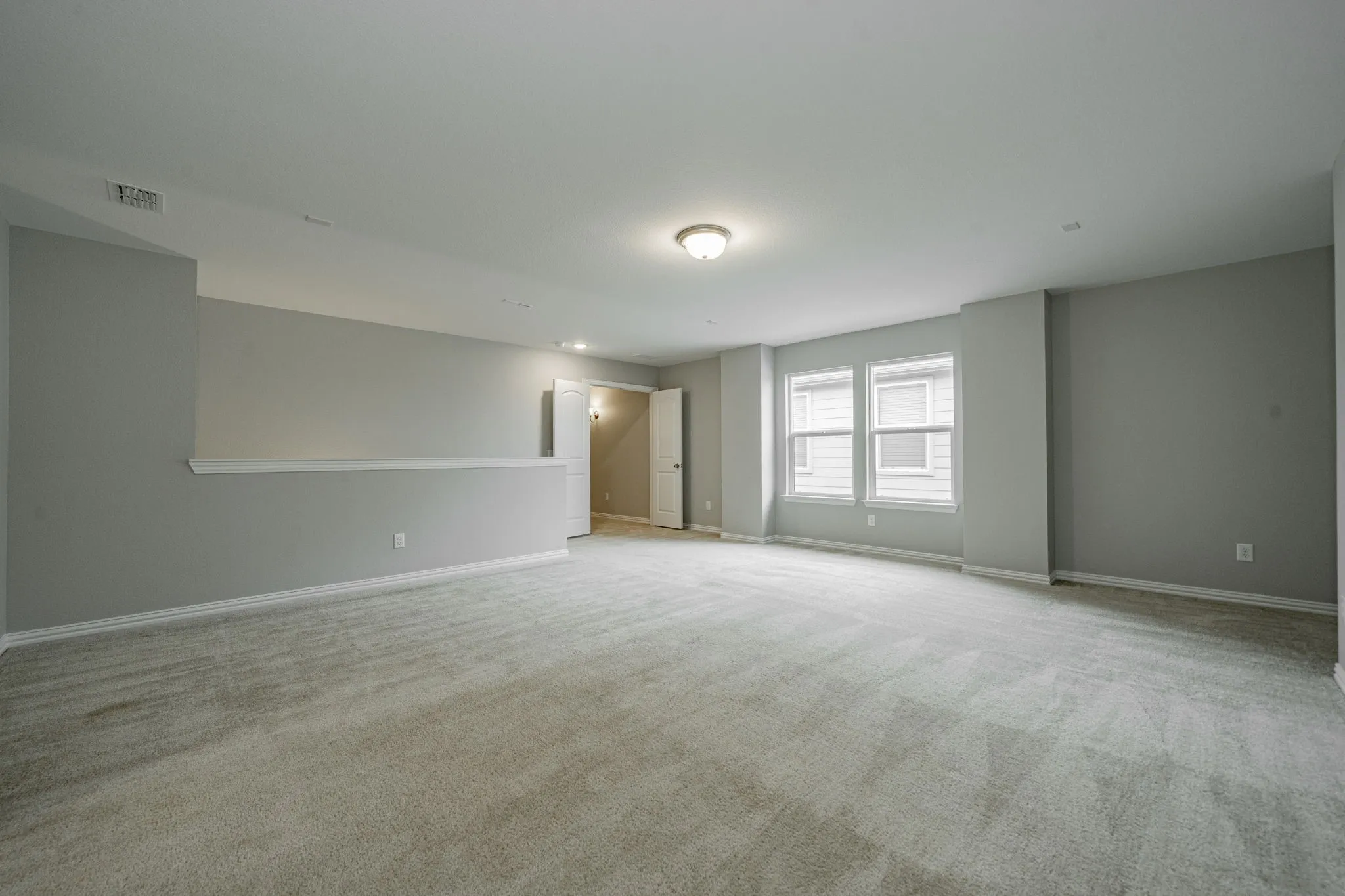 Expansive carpeted area with neutral wall color and natural light from multiple windows