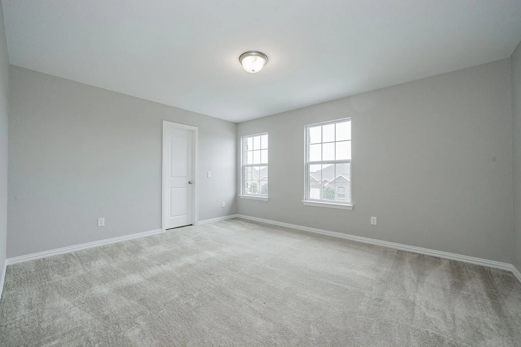 Carpeted room with light gray walls, two windows, and a flush-mount ceiling light