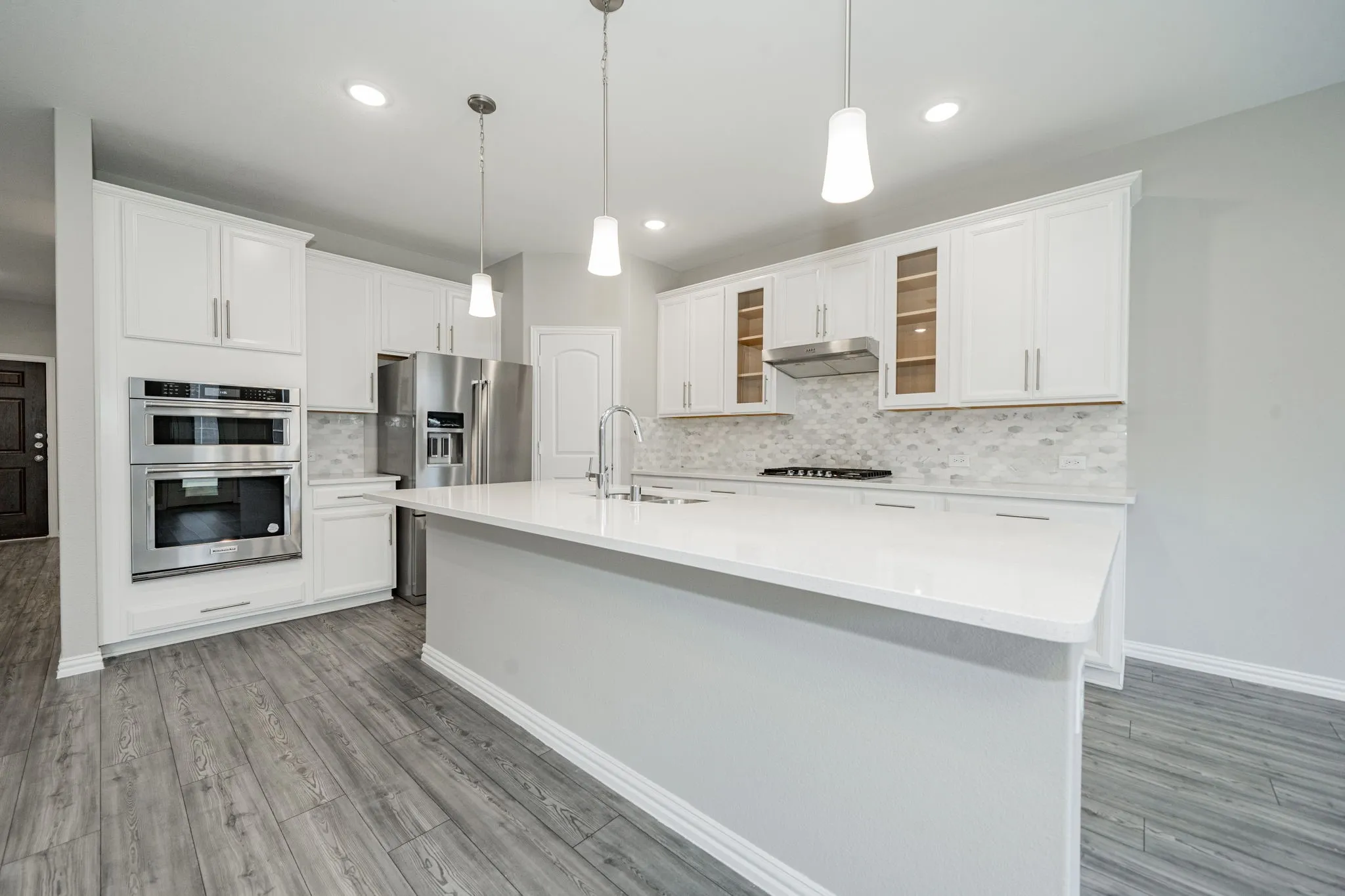 Kitchen featuring an expansive island, white cabinetry, stainless steel appliances, and wood-finish flooring