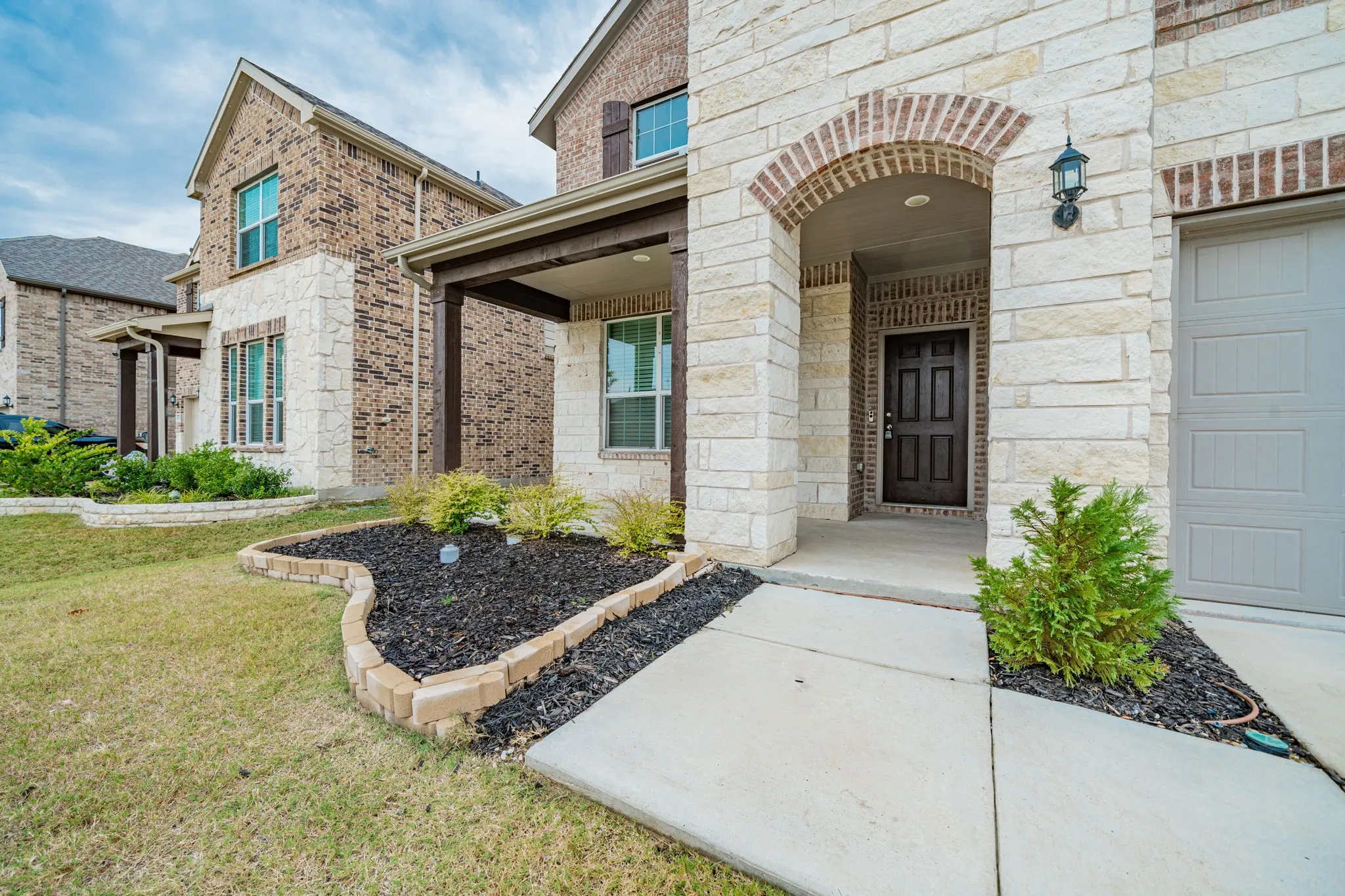 Brick and stone exterior with architectural shutters and a covered entry