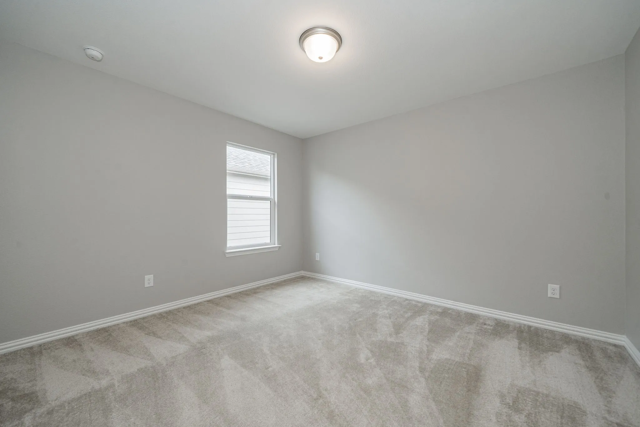 Neutral wall paint, light-toned carpet flooring, a single window, and a flush mount ceiling light