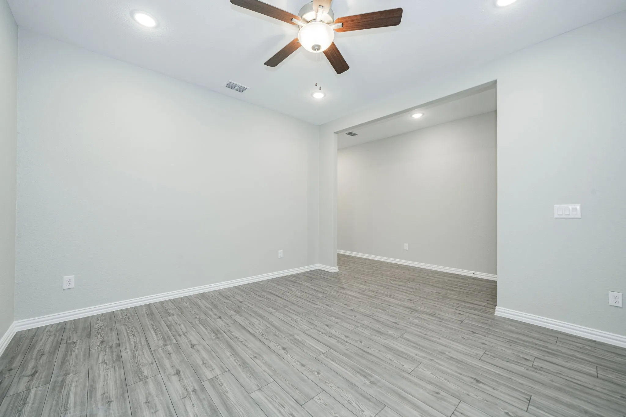 Wood-finish flooring, recessed lighting, ceiling fan, and a wide cased opening