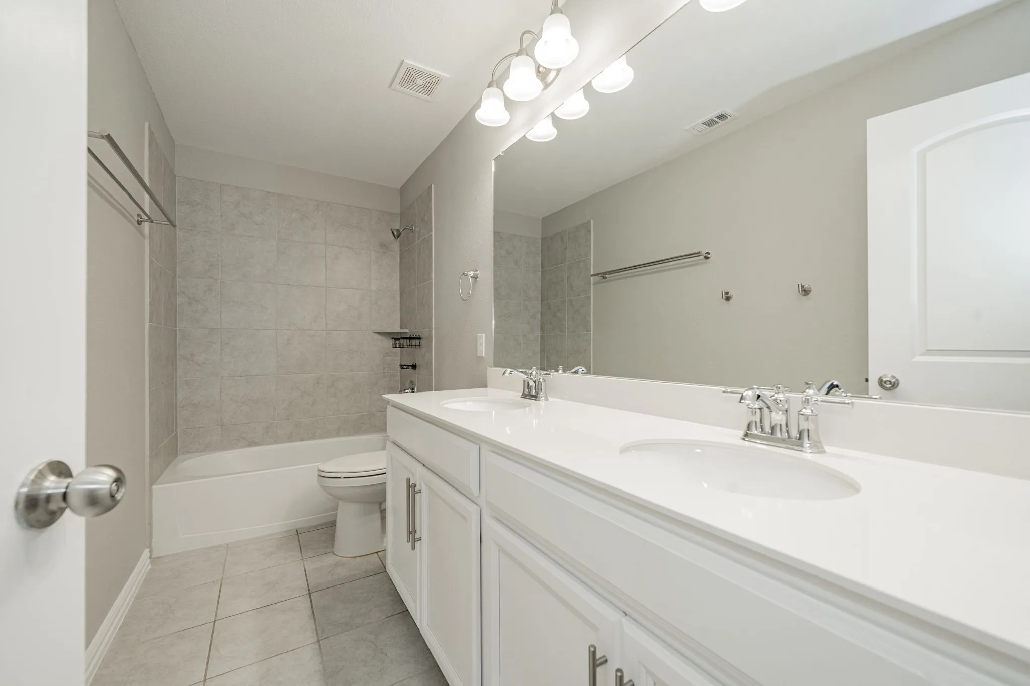 Double vanity with white cabinetry and integrated sinks, brushed nickel fixtures, a large mirror, and overhead lighting
