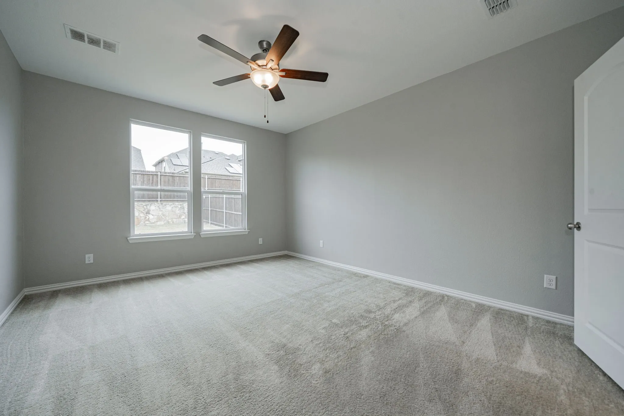 Recessed ceiling fan with integrated lighting, two double-hung windows, light gray wall paint, light-toned carpet flooring, and a white interior door with a round knob